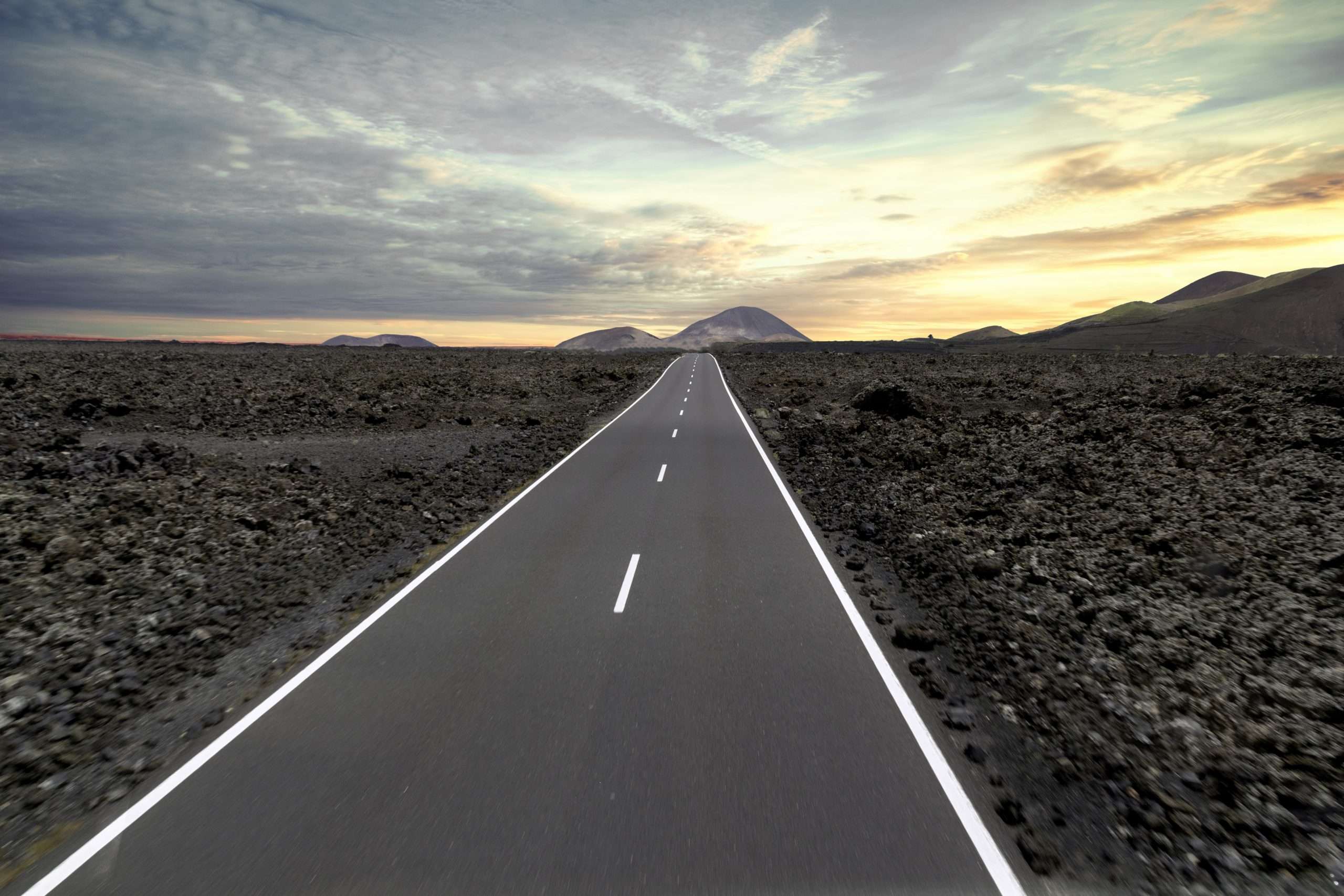 road surrounded by hills and stones during the sunset in the timanfaya national park in spain scaled